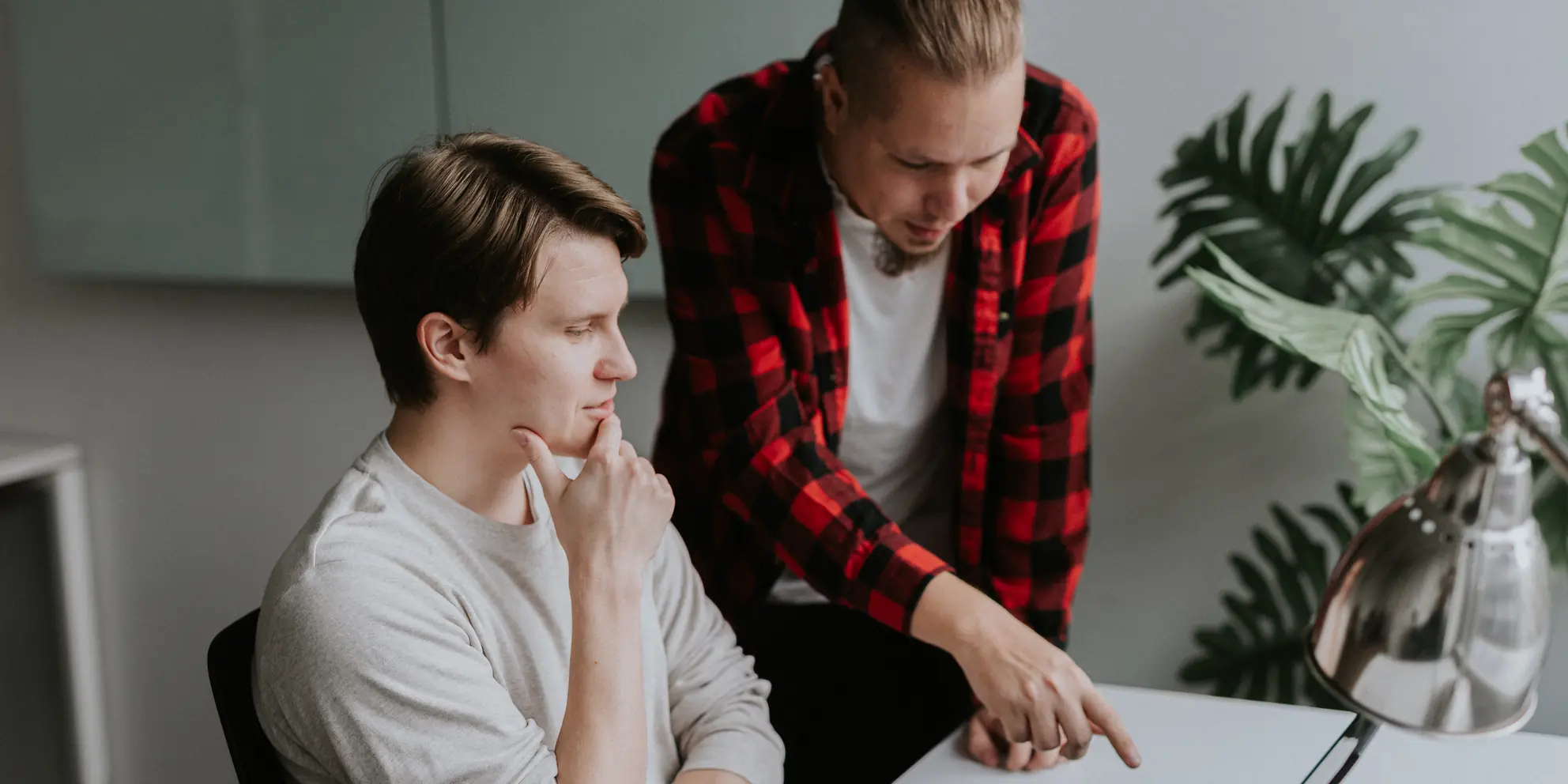 Kaksi Codaonen kehittäjää käy läpi koodia kannettavalta tietokoneelta toimistolla